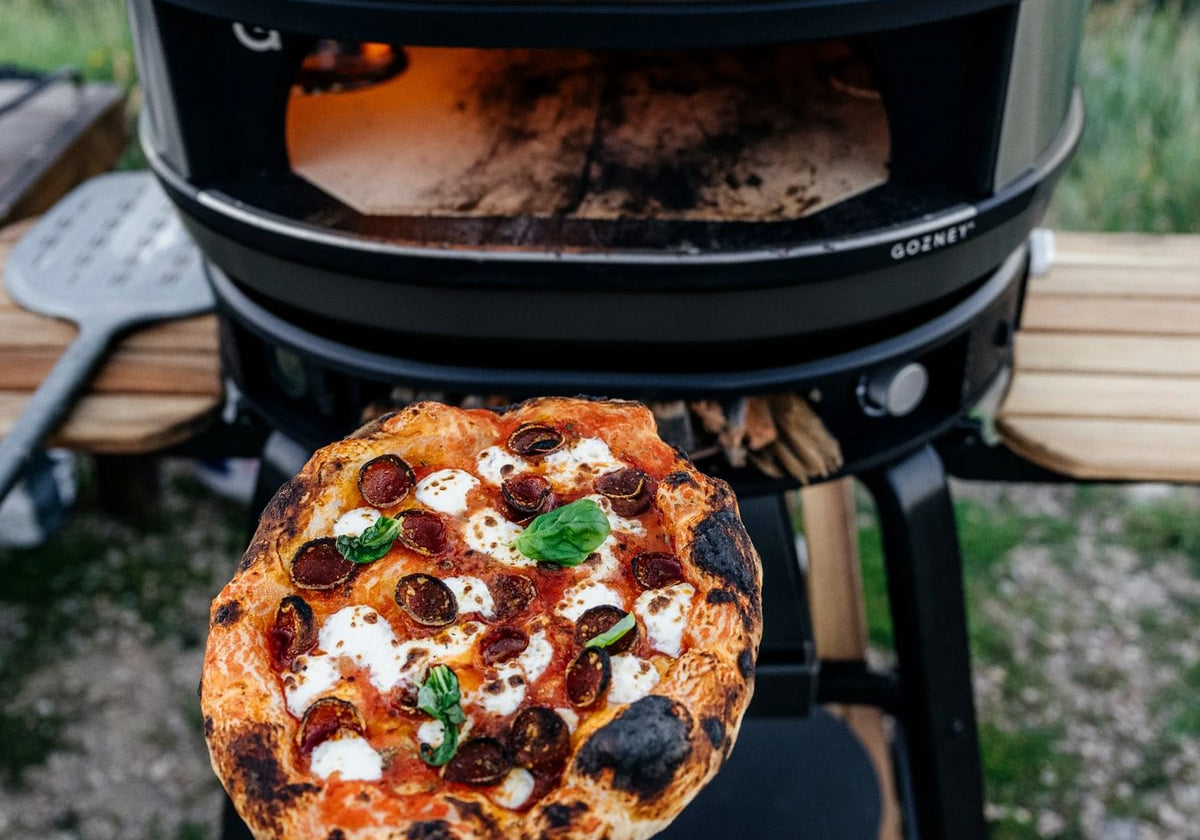 Pizza napolitaine à la mozzarella et au basilic devant un four à pizza Gozney Dome noir