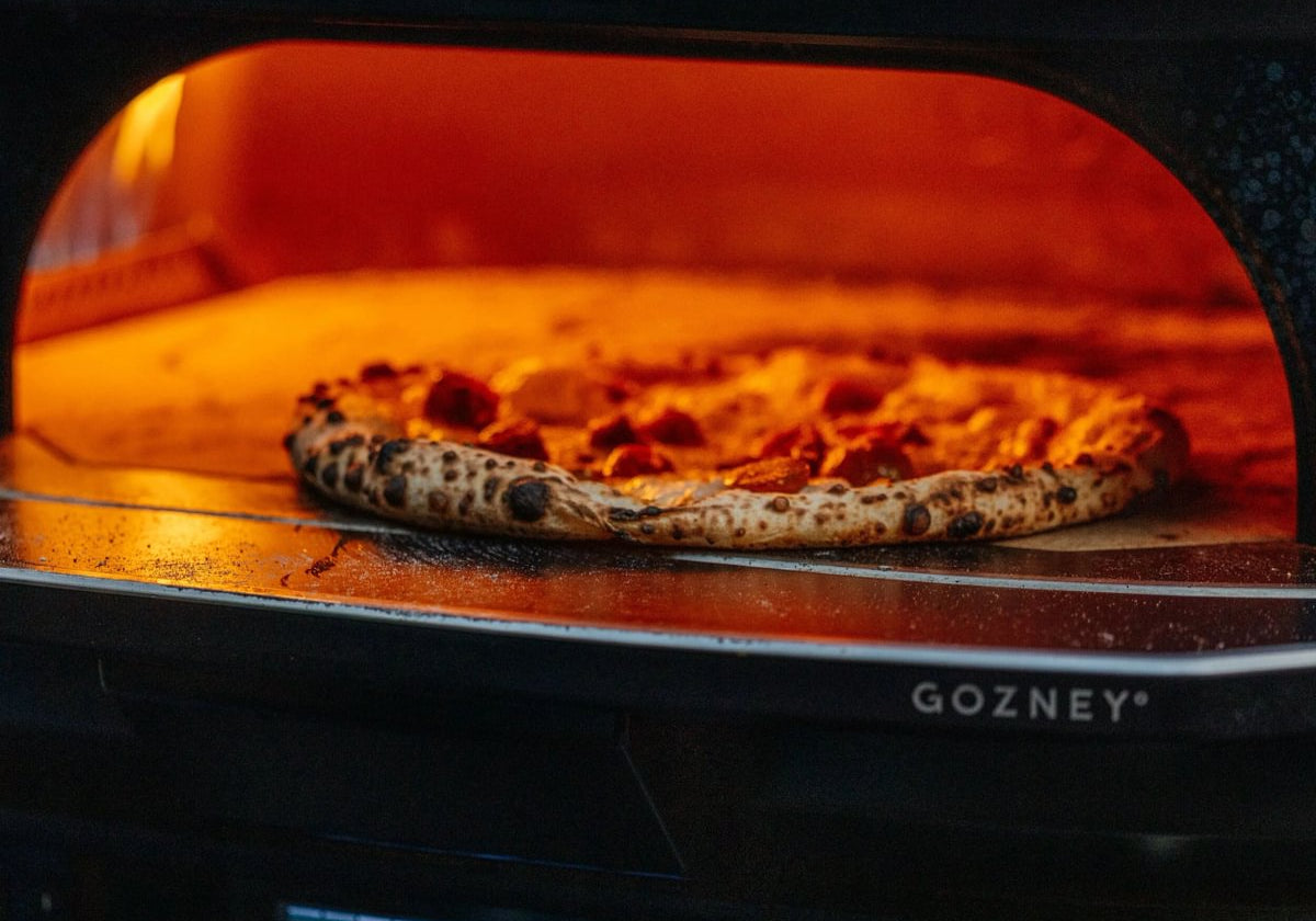 Pizza napolitaine en cuisson sur la pierre d'un four à pizza Gozney Dome Gen 2, chambre incandescente
