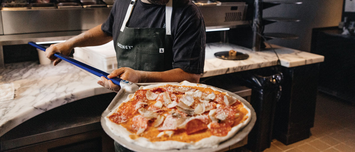 Pizzaiolo qui sort une pizza du four