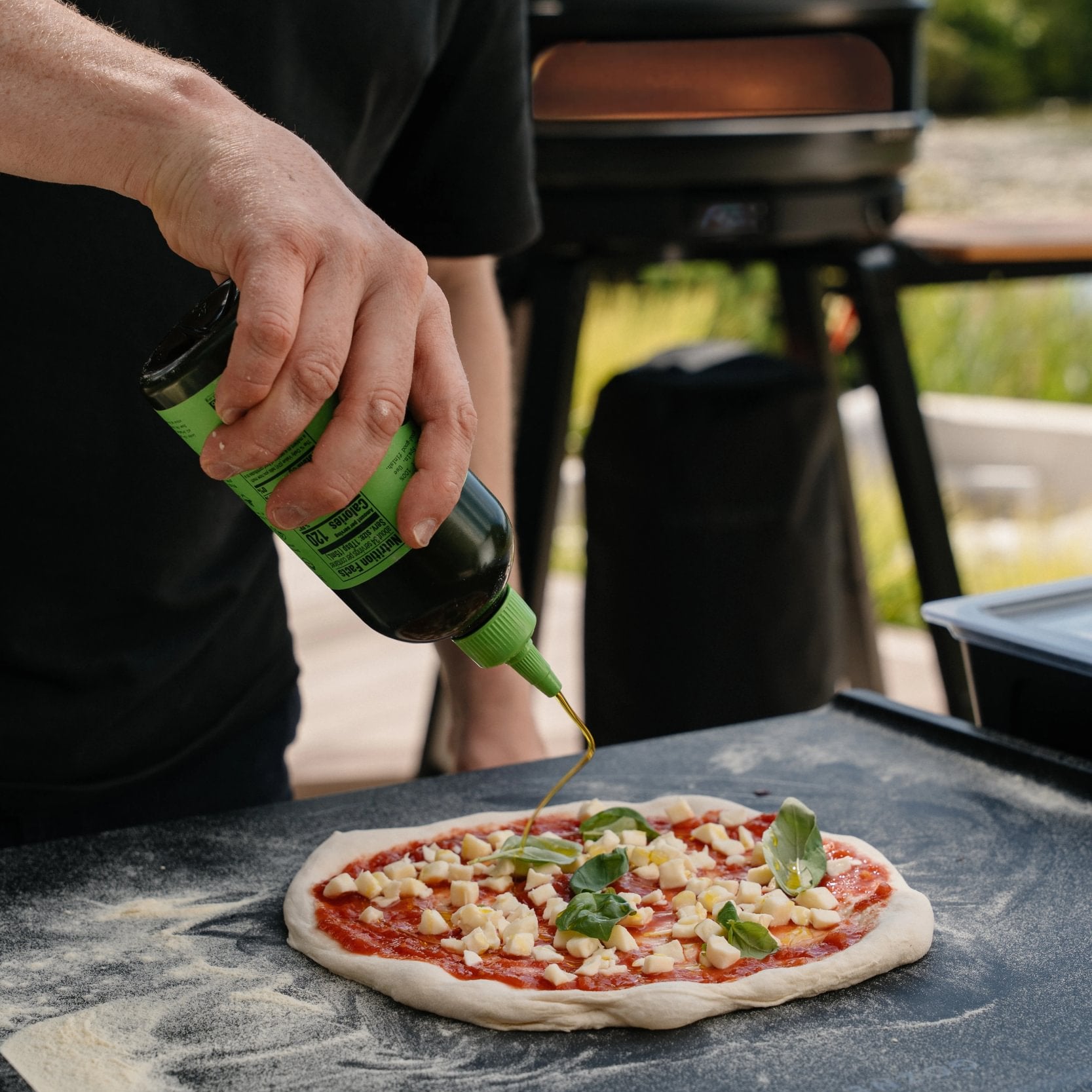 Filet d'huile d'olive sur une pizza margherita avant la cuisson