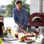 Alfa Moderno 2 Pizze Petit four à pizza hybrid bois propane gaz naturel antique red avec famille qui mange une pizza à table dans cuisine extérieure