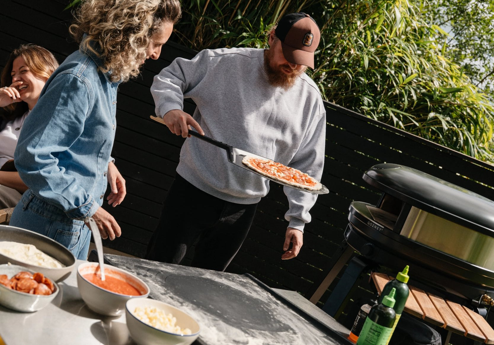 Amis qui préparent et enfournent des pizzas autour d'un four Gozney